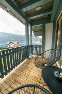 um alpendre com uma mesa e cadeiras e o oceano em Surfers Lodge near Interlaken, at lake with pool em Därligen