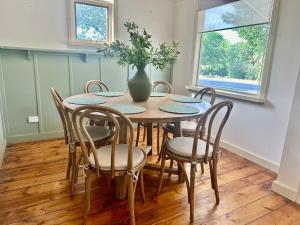 une table de salle à manger avec des chaises et un vase dessus dans l'établissement Cottage on High, à Wedderburn