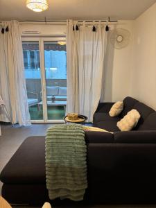 a living room with a black couch and a window at Appart cosy in La Seyne-sur-Mer