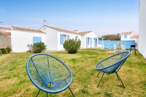 two blue chairs sitting in the grass in a yard at Maison pour 6 - Jardin - Centre de Noirmoutier in Noirmoutier-en-l'lle