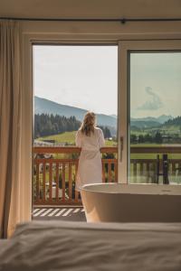 kobieta stojąca na balkonie z wanną w obiekcie Ferienwelt Kesselgrub Hotel in Altenmarkt-Zauchensee w mieście Altenmarkt im Pongau
