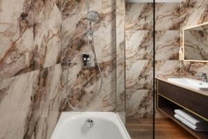 a bathroom with a shower and a white tub at Delta Hotels by Marriott Colchester in Colchester +28 photos