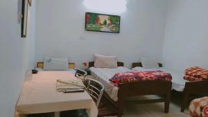 una habitación con dos camas y una mesa y sillas en SOLAN HOSTELz, en Solan