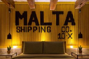 1 dormitorio con 1 cama y una pared amarilla con las palabras "maxuing" en Escape to a Unique 2 Bed Apt in Heart of Valletta, en La Valeta 13 fotos más