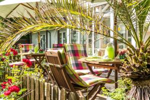 a patio with chairs and tables in a garden at Hotel-Pension Lindenhof in Boltenhagen