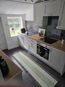 a kitchen with white cabinets and a sink and a window at Jasmyne Cottage in Wainfleet All Saints