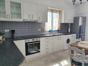 a kitchen with white cabinets and a stove top oven at Aeon Blue in Sikinos +9 photos