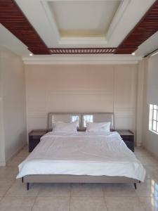 a bedroom with a large bed with white sheets and pillows at Cosy 2 bedroom apartment in Arusha