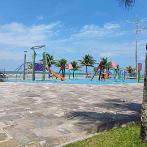 ein Spielplatz am Strand mit Palmen in der Unterkunft Casa Praia Grande pé na areia in Praia Grande