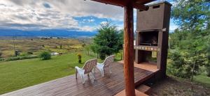 a deck with two chairs and an outdoor oven at Cabaña Esquina Siracusa in Villa Yacanto