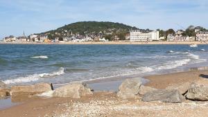 a beach with rocks and the ocean and a mountain at Les Tennis - Superbe appartement avec parking in Houlgate