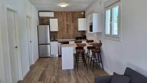 Una cocina con barra con taburetes y refrigerador. en Passive House con piscina y jardín privado, en Novo Sancti Petri