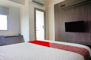 a bedroom with a bed and a tv on a wall at OYO 91593 San San Rooms Apartment Gunung Putri Square in Parungdengdek