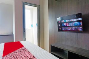 a bedroom with a bed with a flat screen tv on the wall at OYO 91593 San San Rooms Apartment Gunung Putri Square in Parungdengdek +21 photos