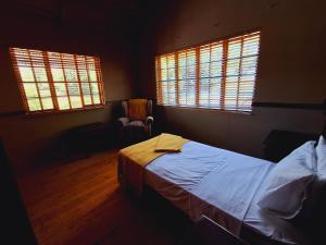 a bedroom with a bed and two windows at Strathavon Cottage in Machadodorp