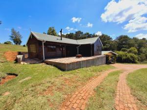 a house on a hill with a dirt road in front of it at Strathavon Cottage in Machadodorp