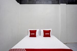 a white bed with two red pillows on it at Hotel O Villa A1 in Tretes