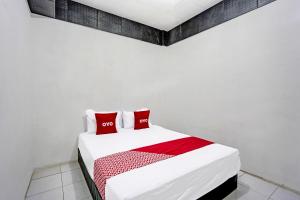 a white bed with two red pillows on it at Hotel O Villa A1 in Tretes +25 photos