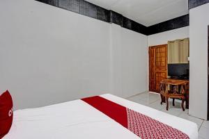 a bedroom with a bed with a red and white blanket at Hotel O Villa A1 in Tretes