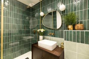 a green tiled bathroom with a sink and a mirror at Maison Zellige - Rooftop - Gruissan Center in Gruissan