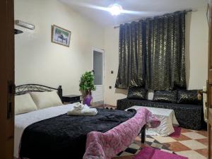 a bedroom with a large bed and a couch at Maison d'hôtes de Zaida in Zeïda