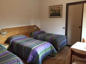 2 bedden in een hotelkamer met gestreepte lakens bij Affittacamere Giudici in Lentate sul Seveso