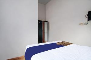 a bedroom with a bed with a blue and white blanket at Hotel O Oklahoma Homestay Syariah in Pekanbaru