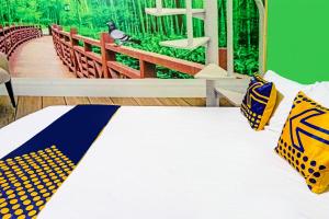 a bedroom with a bed with yellow and blue pillows at OYO 91697 Nyaman Homestay Syariah in Pare