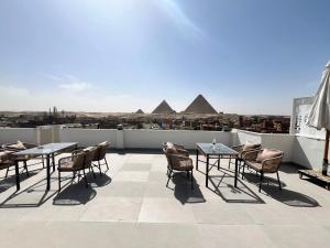 a patio with tables and chairs on a roof with pyramids at Pyramid hotel in Cairo