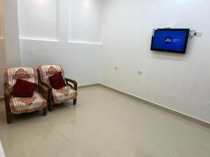 a room with two chairs and a tv on a wall at Hotel Jayaditya Palace Near Ram Mandir walking Distance in Ayodhya