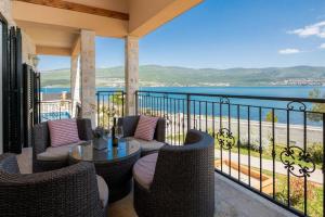 a balcony with chairs and a table with a view of the ocean at Seafront Villa Noah with heated pool in Pridraga