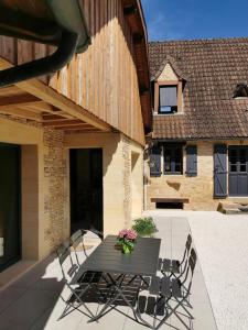 une table noire avec des chaises et des fleurs sur une terrasse dans l'établissement Lou fredou, à Saint-Amand-de-Coly