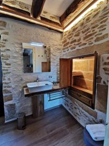 une salle de bain avec un lavabo et un mur en pierre dans l'établissement Lou fredou, à Saint-Amand-de-Coly