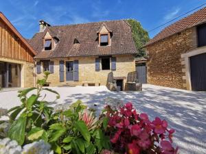 une maison en briques avec des fleurs devant elle dans l'établissement Lou fredou, à Saint-Amand-de-Coly