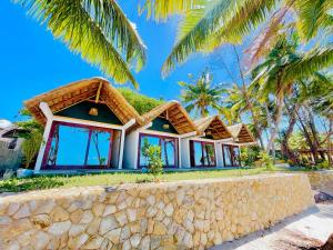 a house on a beach with palm trees at Bush Beach Hostel in Vilanculos