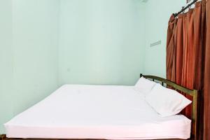a small bedroom with a white bed with a curtain at Hotel O Homestay Bang HajiNearLapangan Penujak ( Inen Gonggang) in Praya
