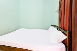 a bed with white sheets and a pillow on it at Hotel O Homestay Bang HajiNearLapangan Penujak ( Inen Gonggang) in Praya +19 photos
