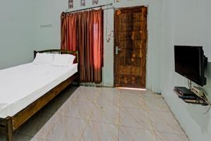 a room with a bed and a door and a television at Hotel O Homestay Bang HajiNearLapangan Penujak ( Inen Gonggang) in Praya