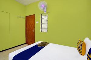 a green room with a bed and a fan at SPOT ON 91716 Kost Yy Syariah in Mojokerto