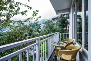 ダラムシャーラーにあるHigh Sky Resort - Best Luxury Hotel in Dharamkotの椅子とテーブルが置かれたバルコニー