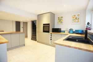 une grande cuisine avec des placards blancs et un évier dans l'établissement 19th-century fishermans cottage, à Corton