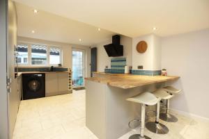 une cuisine avec un comptoir et des tabourets dans une pièce dans l'établissement 19th-century fishermans cottage, à Corton