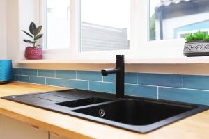 - un évier noir dans une cuisine avec fenêtre dans l'établissement 19th-century fishermans cottage, à Corton 15 autres photos