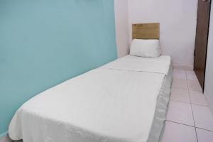 a white bed in a room with a blue wall at Hotel O Solo Baru Homestay Syariah in Jodoh
