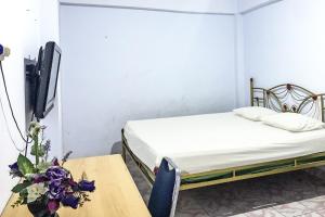 a bedroom with a bed and a tv and flowers at Hotel O Surya HotelNearTaman Anggrek Pkk Watansoppeng in Watansopeng