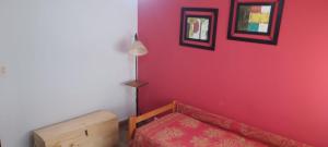 1 dormitorio con pared roja y cama de madera en LAS HERMANAS, en Tandil