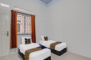 zwei Betten in einem Zimmer mit Fenster in der Unterkunft Hotel O Rumah Singgah Kinaya Syariah in Parit + 19 Fotos