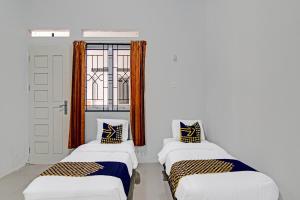 zwei Betten in einem Zimmer mit Fenster in der Unterkunft Hotel O Rumah Singgah Kinaya Syariah in Parit