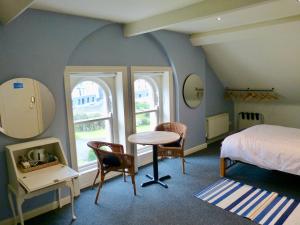 a bedroom with a bed and a table and two windows at Downhill Beachhouse Group Accommodation in Castlerock