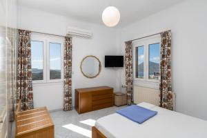 a bedroom with a bed and a mirror and windows at Uncle John's House with View in Tripiti